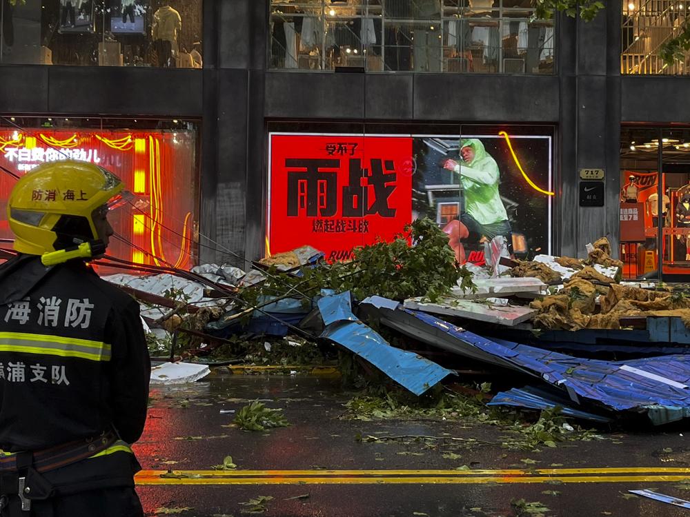 A firefighter stands near debris along a business street in the aftermath of Typhoon Bebinca in Shanghai, China on Monday.