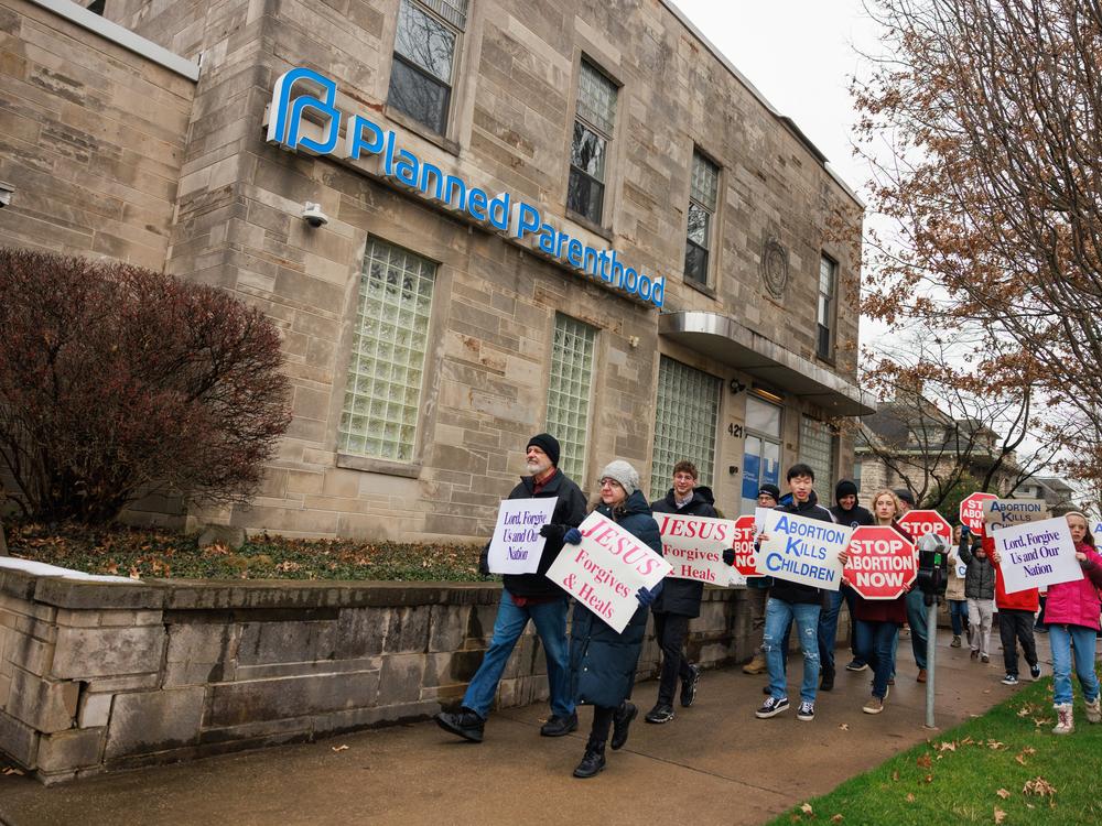 Anti-abortion protesters march past the Planned Parenthood in Bloomington, Ind., after the Rally for Life march in January 2023. The facility offers birth control and testing for sexually transmitted diseases now that abortion is banned in Indiana.