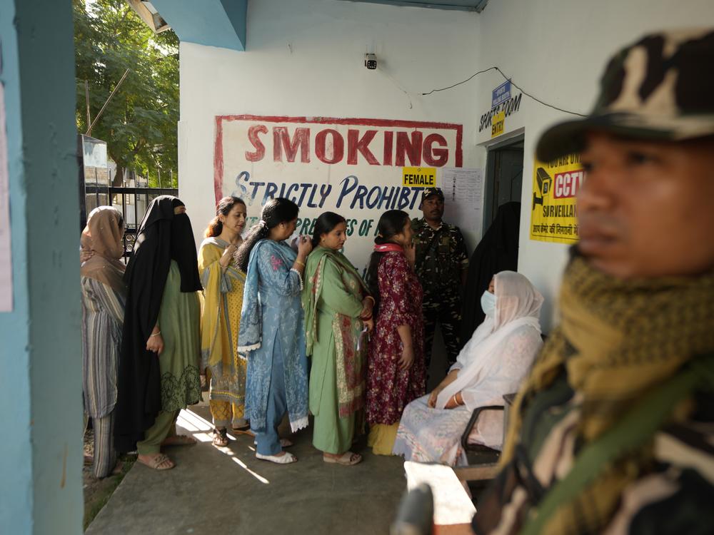 Paramilitary soldiers stand guard as people queue up to vote during the first phase of the Jammu and Kashmir assembly election, in Kishtwar, India, on Wednesday.