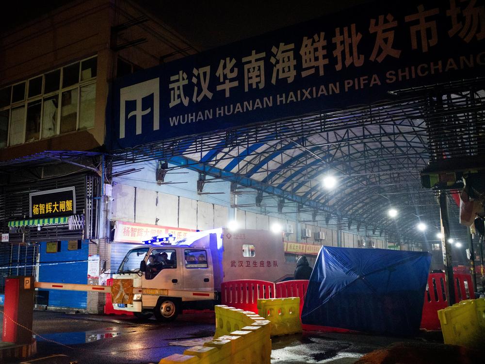 A vehicle belonging to the Wuhan Hygiene Emergency Response Team drives past the shuttered Huanan Seafood Wholesale Market in Wuhan, China, on Jan. 11, 2020 — the day that the Wuhan health commission reported what is believed to be the first death from COVID-19. A new study points to raccoon dogs sold in the market as the likely source of the spillover of the SARS-CoV-2 virus from animals to humans.