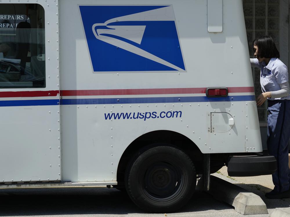 A U.S. Postal Service employee works outside while making deliveries in Northbrook, Ill., in June.