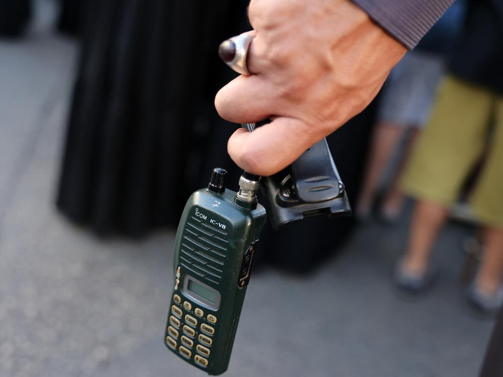 A man holds an Icom walkie-talkie after he removed the battery during a funeral of people killed when hundreds of paging devices exploded in a deadly wave across Lebanon the previous day, in Beirut's southern suburbs on Sept. 18.