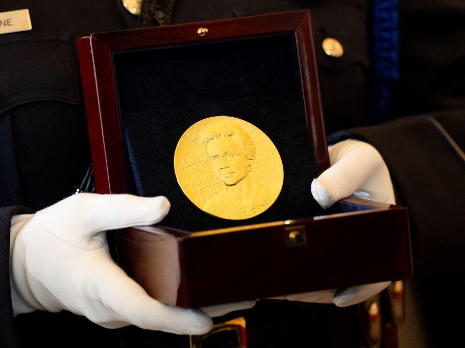 A member of the U.S. Capitol Police carries a Congressional Gold Medal for Katherine Johnson, one of NASA's 