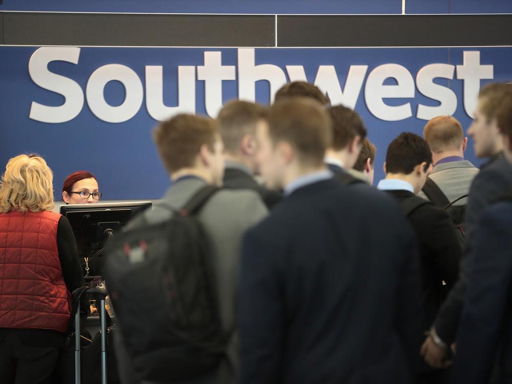 Passengers line up to check in at a Southwest Airlines ticket counter at Midway Airport in Chicago. Southwest will soon change its seating policy.
