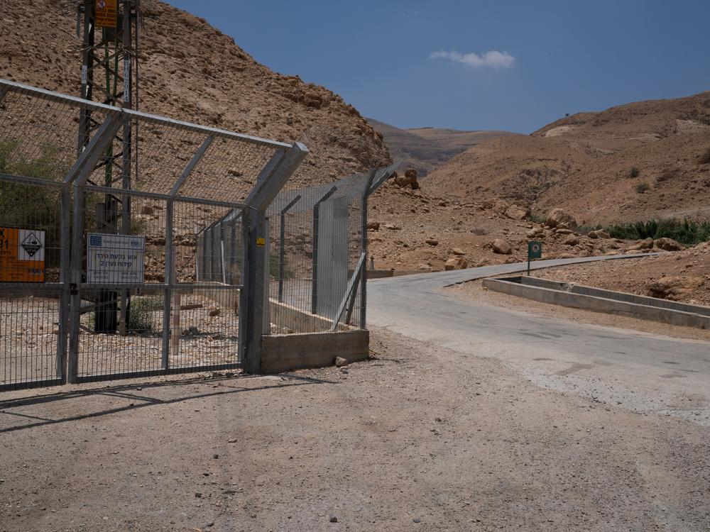 An Israeli-owned well is protected by a fence across from where the spring-fed channel brings water along the road to the pool and for agriculture in Al-Auja. 