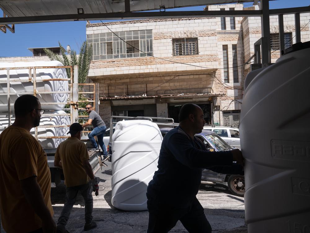 Samer Shini (far left) owns a shop that sells water tanks in Ramallah. He says these days he can sell 10 tanks in an hour. 
