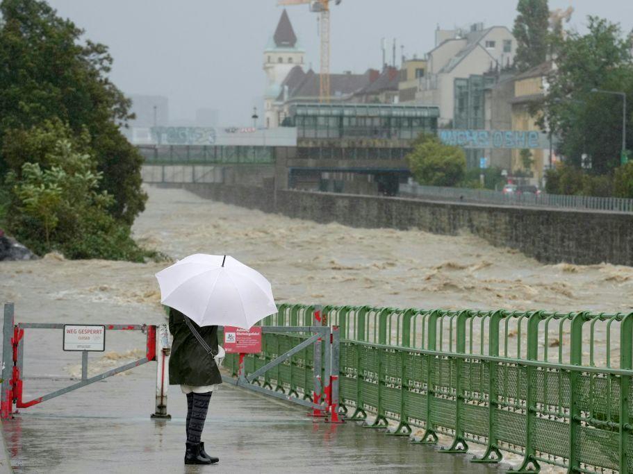 A pedestrian looks at the high level of the Wien River in Hutteldorf, Vienna, during heavy rainfall on September 15, 2024.  Parts of Austria, the Czech Republic, Hungary, Romania, and Slovakia were hit by high winds and unusually fierce rains in September. 