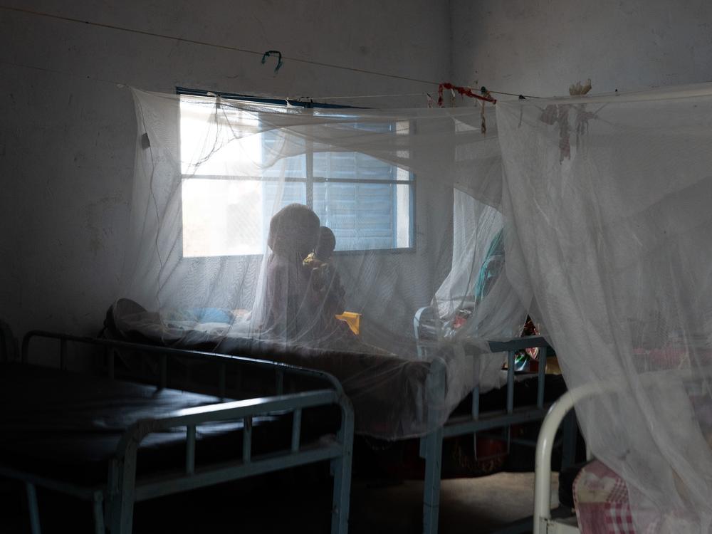 One of the women who's brought her baby to the malnutrition clinic in Farchana. They're sitting under mosquito nets.
