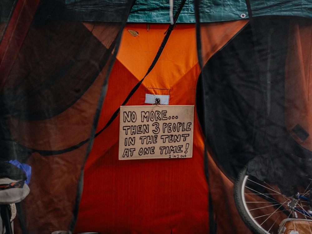 A sign hangs on a tent stating how many people can be inside at one time in Chicago's Humboldt Park.