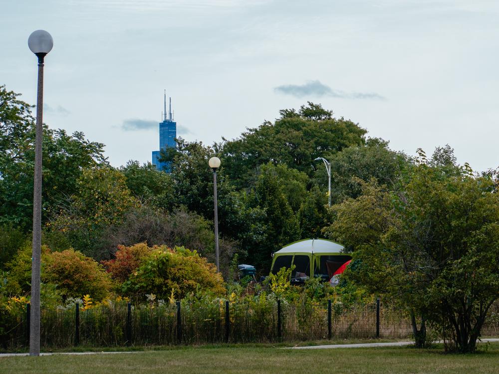 The Chicago skyline emerges behind an encampment in Humboldt Park.