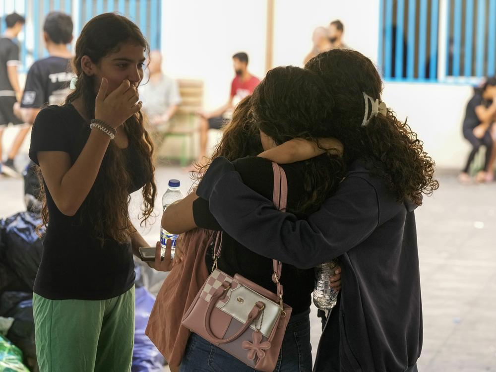 Displaced youth hug as they take shelter at a school in Beirut, after fleeing the Israeli airstrikes in the south with their families on Thursday