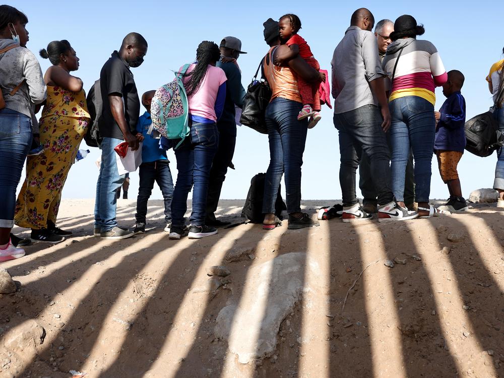Immigrants from Haiti, who crossed through a gap in the U.S.-Mexico border barrier, wait in line to be processed by the U.S. Border Patrol on May 20, 2022 in Yuma, Arizona. 