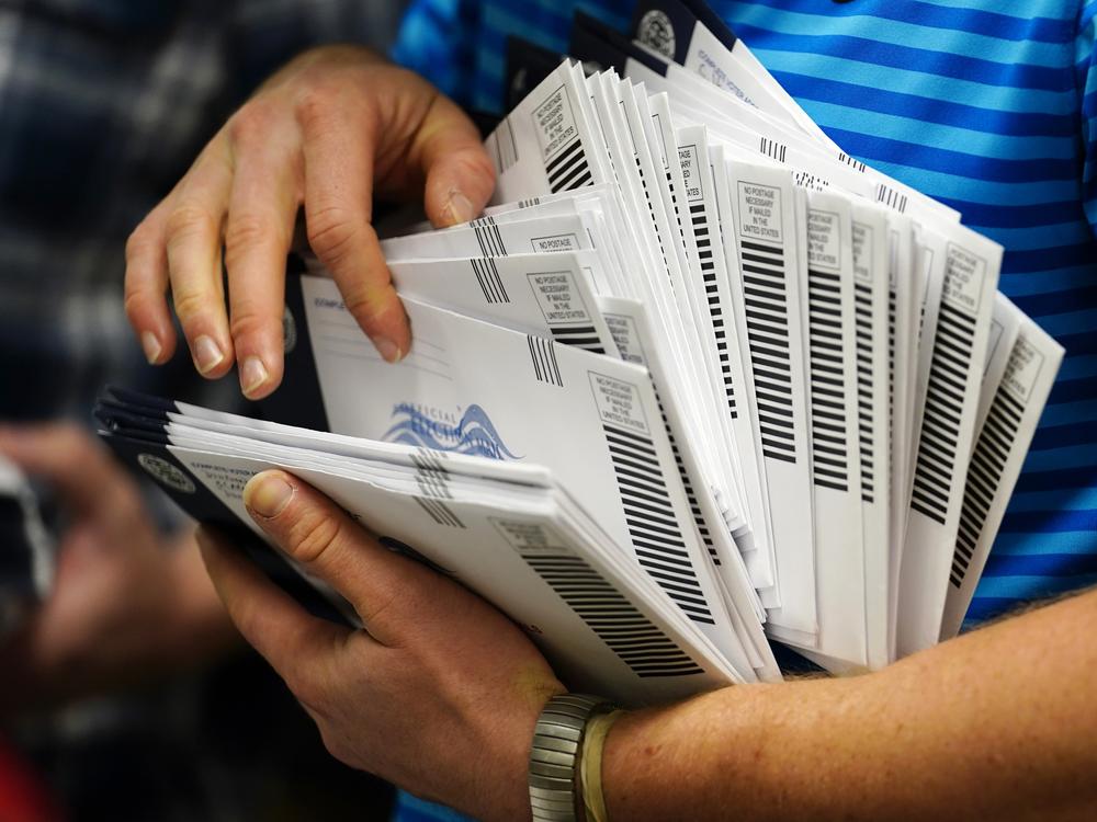 An election official organizes mail-in ballots to be sorted for the 2020 general election in West Chester, Pa.