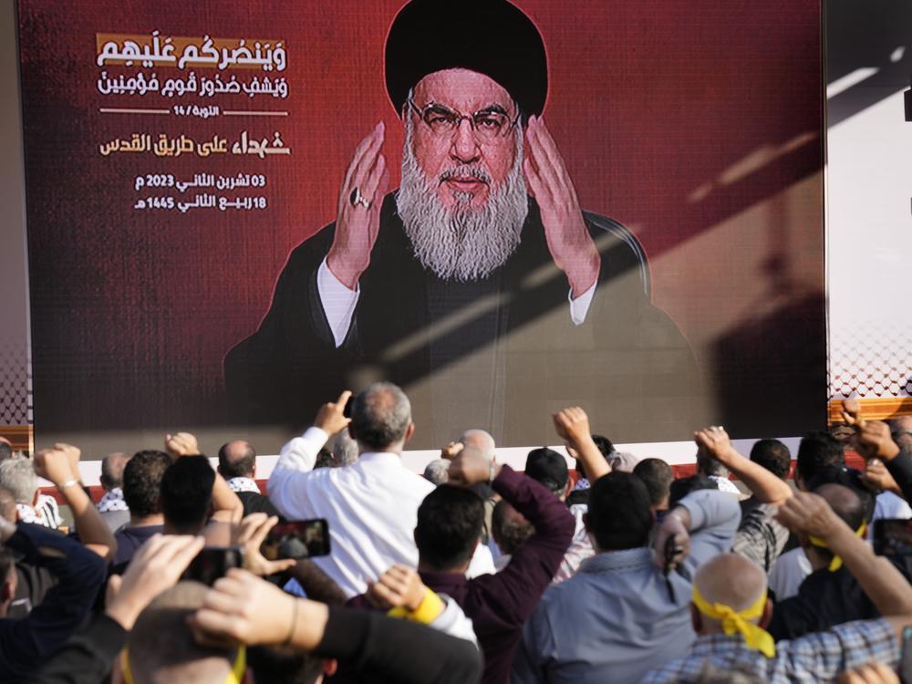 Supporters of the Iranian-backed Hezbollah group raise their fists and cheer as Hezbollah leader Hassan Nasrallah appears via a video link, during a Nov. 3, 2023, rally in Beirut to commemorate Hezbollah fighters who were killed in South Lebanon while fighting against the Israeli forces.