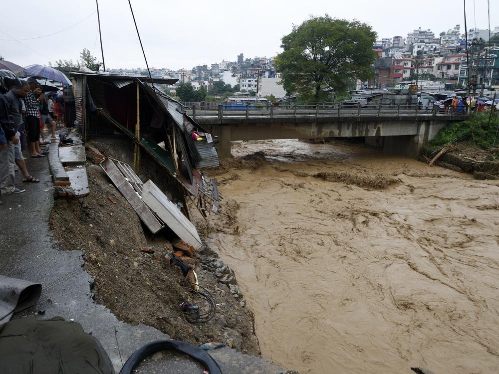 People gather at the edge of the Bagmati River in spate after heavy rains in Kathmandu, Nepal, Saturday, Sept. 28, 2024. 