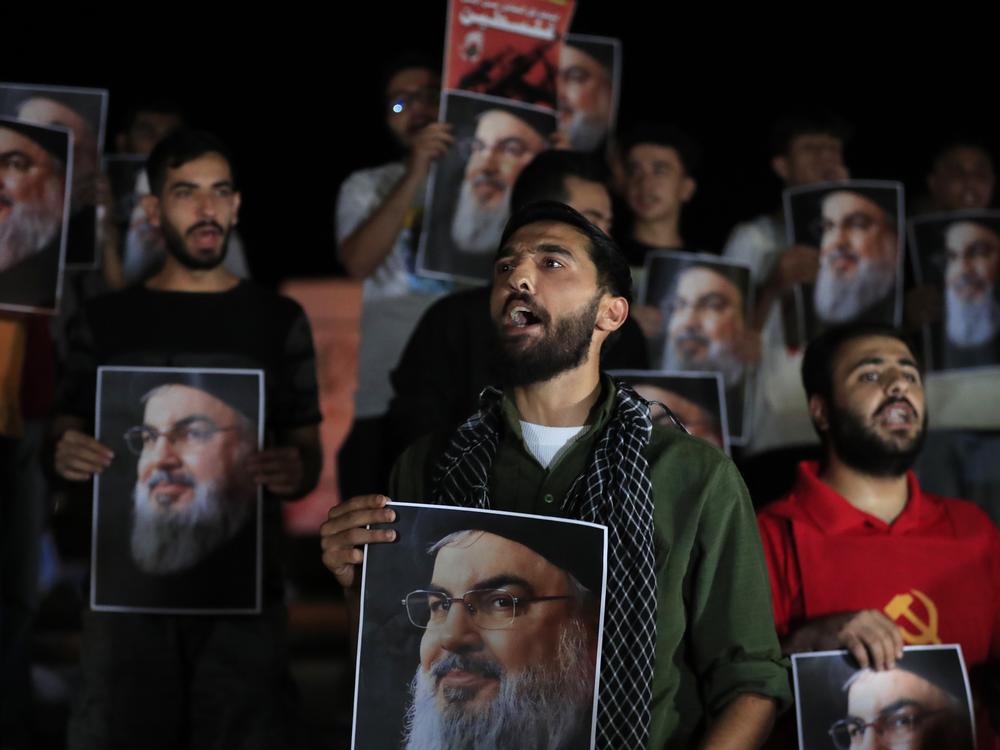 Lebanese and Palestinian men hold portraits of Hezbollah leader Hassan Nasrallah during a protest in the southern port city of Sidon, Lebanon, on Sept. 28.