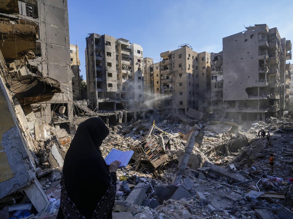 A woman reads the Quran at the site of the assassination of Hezbollah leader Hassan Nasrallah in Beirut's southern suburbs, Sunday.