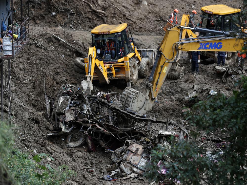 Earthmovers remove mangled automobile debris from a landslide caused by heavy rains in Kathmandu, Nepal, Sunday, Sept. 29, 2024.