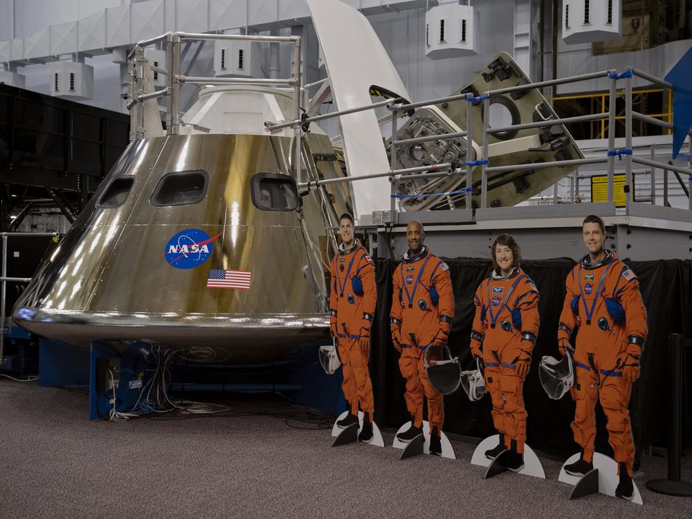 Cardboard cutouts of the Artemis II crew next to the Orion spacecraft mockup.