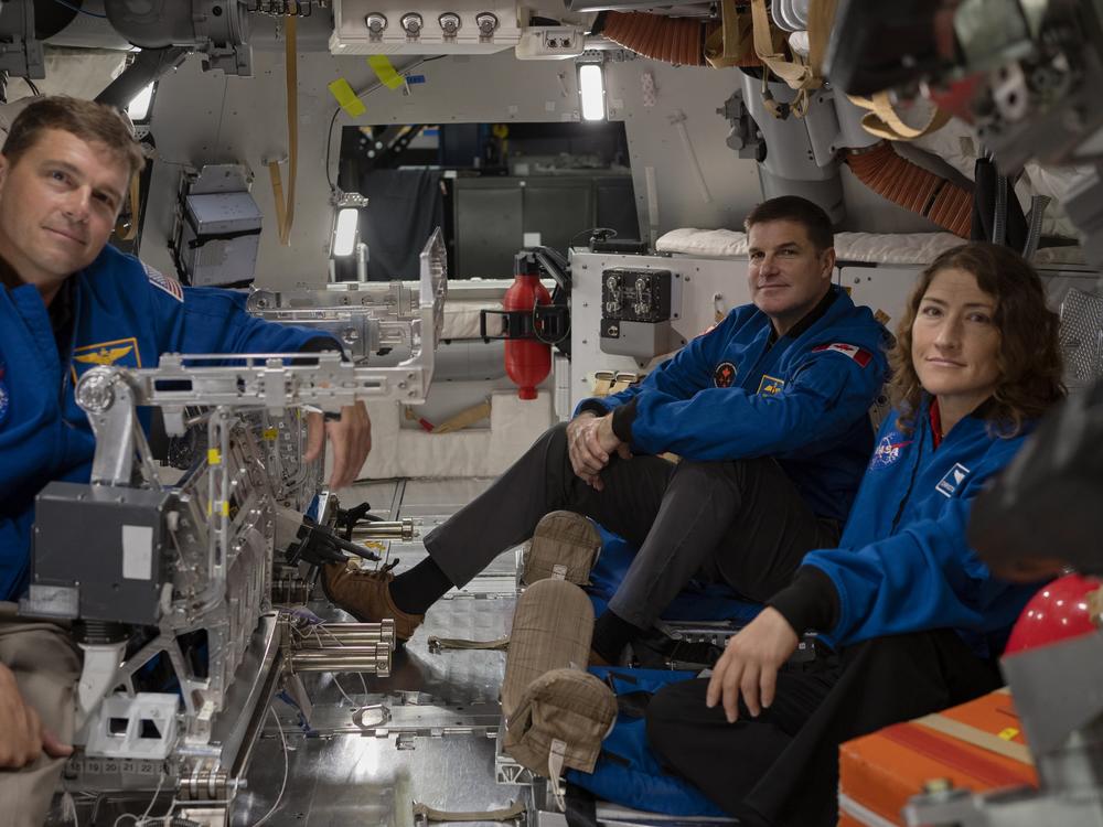 From left to right: Astronauts Reid Wiseman, Jeremy Hansen and Christina Koch settle in inside the Orion spacecraft mockup.