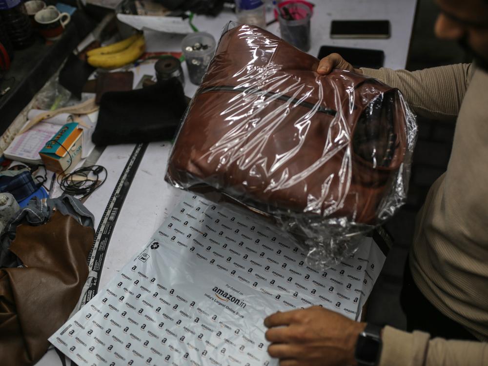 A worker packs a leather jacket in an Amazon India shipping bag at a workshop in the Dharavi area of Mumbai, India, on Jan. 5, 2022.
