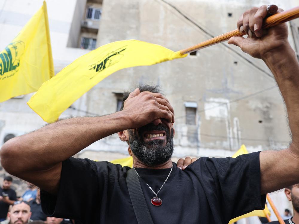 A man reacts on while holding a Hezbollah flag during the funeral on Sept. 18 in Beirut for people killed after pagers exploded in a deadly wave across Lebanon the previous day.