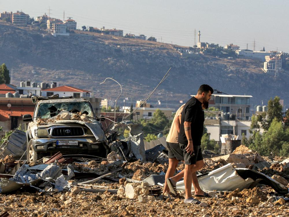 People inspect the site of an Israeli airstrike in Jiyeh along the highway linking Beirut to the southern city of Sidon on Sept. 25. In south Lebanon, a stronghold of Hezbollah, Israeli warplanes bombed villages for a third day on Sept. 25, after airstrikes earlier in the week killed at least 558 people in the deadliest day of violence since the 1975-1990 civil war.