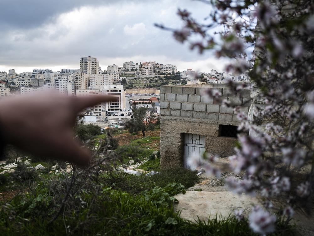 Mohammed Abu Eisheh, whose son Anas Abu Eisheh has been charged with the murder of Ahmad Abu Markhiya, points to a storage room with a white wooden door where prosecutors say the crime took place. The four rows of cinder blocks above the storage room make up the wall of the terrace where the victim and his accused killer drank tea shortly before the murder.