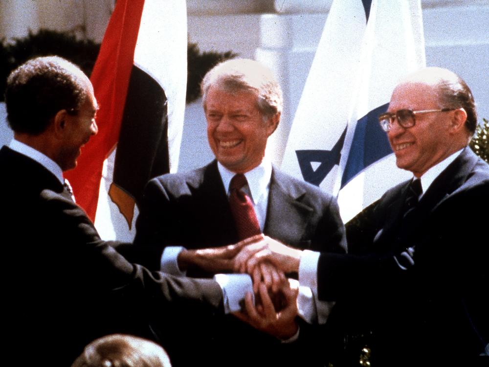 Sadat (from left), Carter and Begin clasp hands outside the White House on March 26, 1979, as they completed signing of the peace treaty between Egypt and Israel in Washington. Carter's efforts were the first major push by <a href=