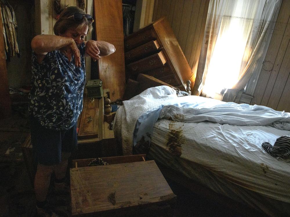Janice Whitley wipes her face while working to find valuables from her 93-year-old mother's bedroom in the aftermath of Hurricane Helene in Old Fort, North Carolina.