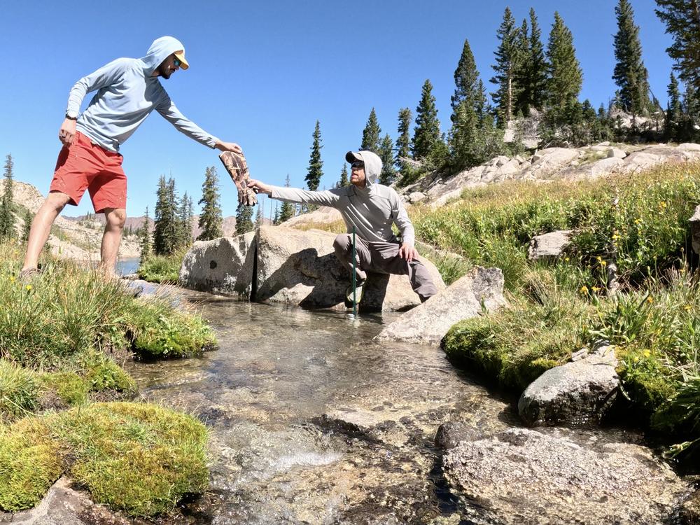 Matthew Morriss is handing Scott Hotaling insulated gloves as they install a water level gage in a stream below the White Pine rock glacier in Little Cottonwood Canyon, UT.