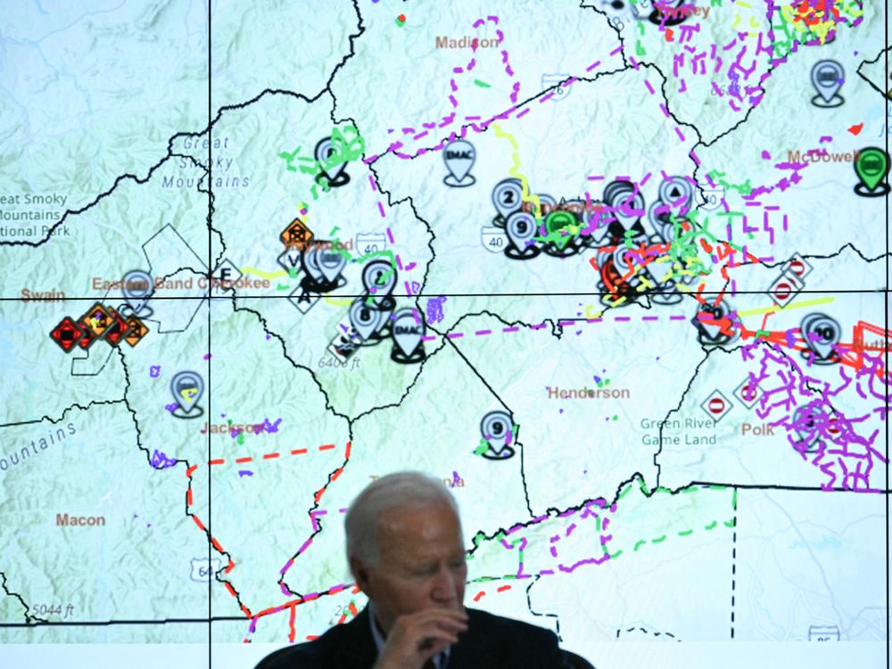 President Biden talks with state officials at an emergency operations center in Raleigh, N.C., with a map of the area hit by Hurricane Helene behind him.