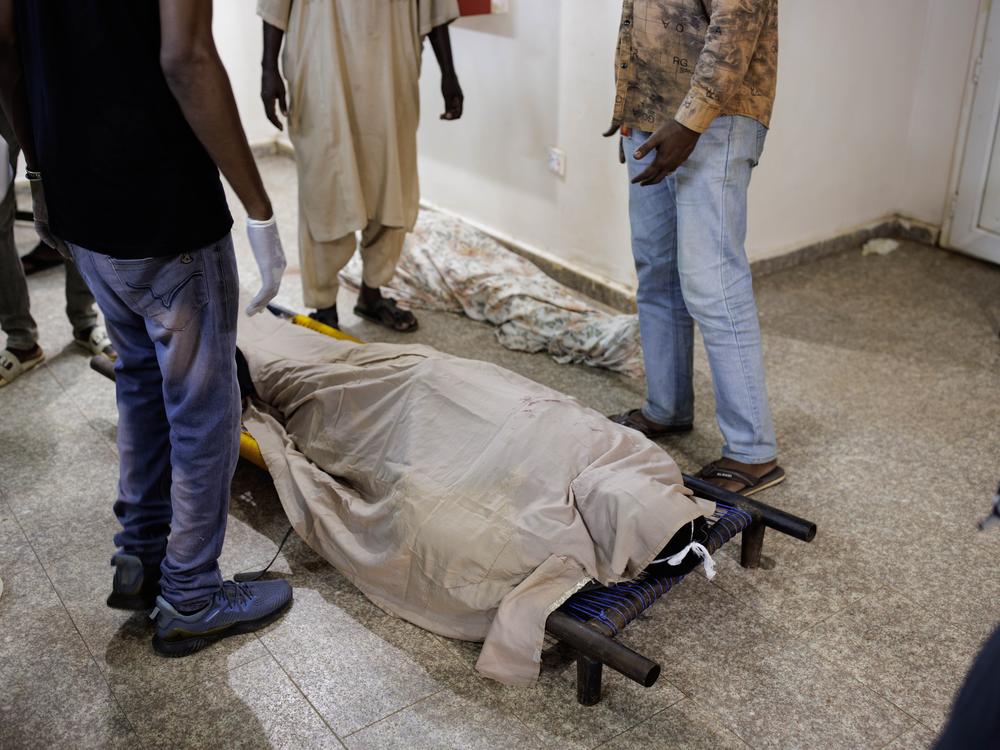 People surround the bodies of two shelling victims as they lie on a corridor floor.
