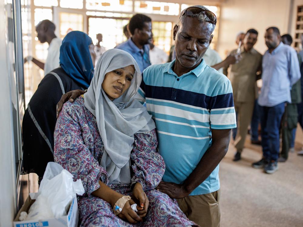 A husband comforts his wife, injured by shelling, in a hallway at the Al Nao Hospital.