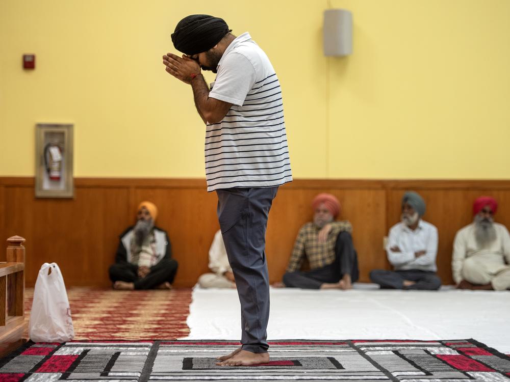 A man lowers his head in prayer at the temple.