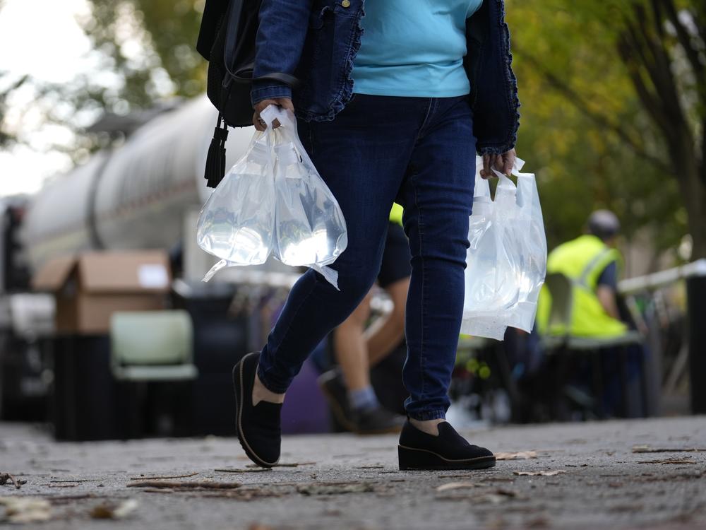 A person carries bags of fresh water after filling up from a tanker at a distribution site in the aftermath of Hurricane Helene on Wednesday in Asheville, N.C.