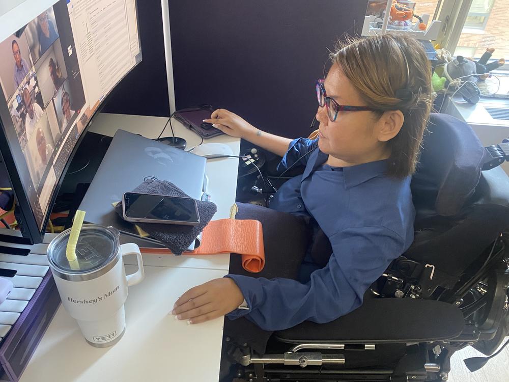 Haly's work colleagues don't know how disabled she is. But with her fingers placed on a trackpad, she can control her computer and run her team meeting.