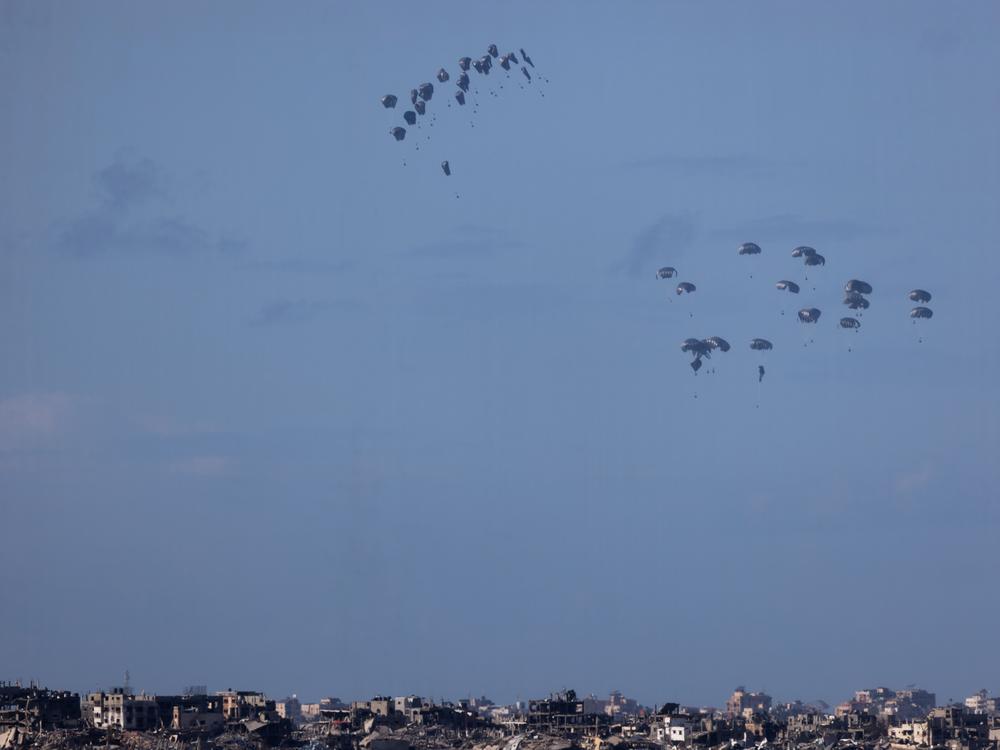 Humanitarian aid falls from planes over northern Gaza as seen from Israel's southern border with the Gaza Strip on March 7.