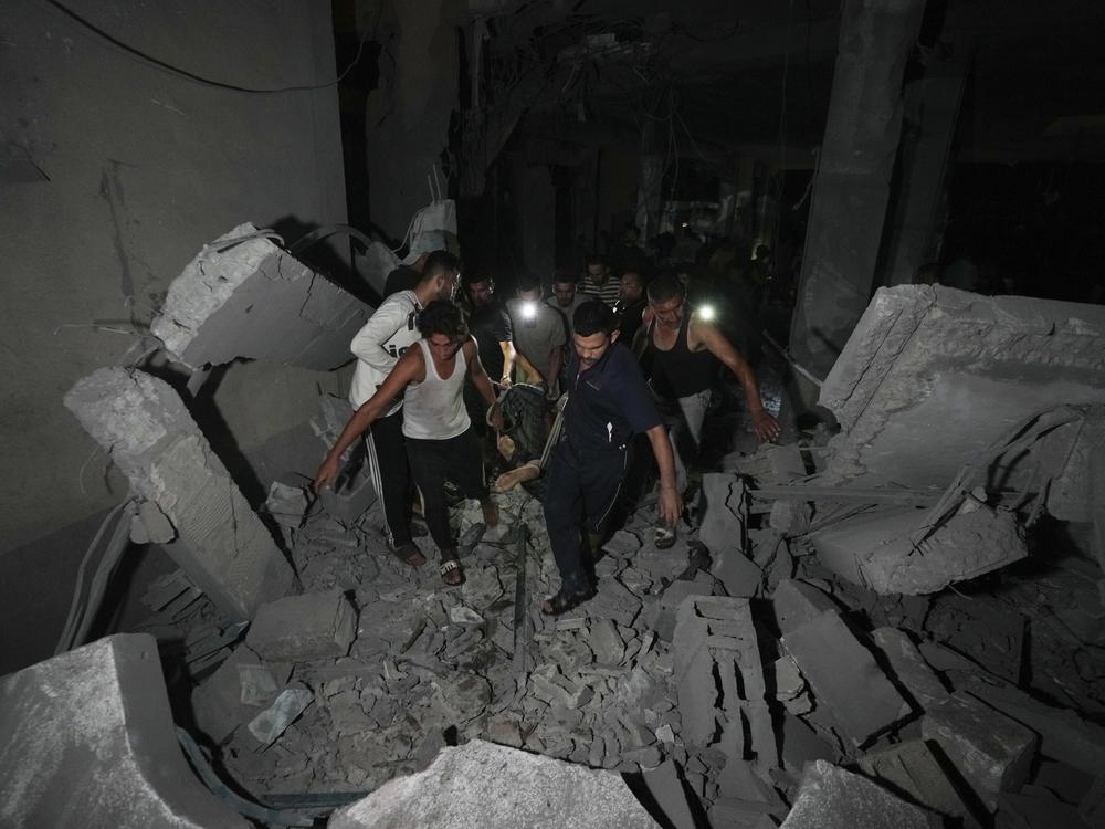 Palestinians carry the body of a person who was found under the rubble of a destroyed mosque following an Israeli airstrike in Deir al-Balah, on Sunday.