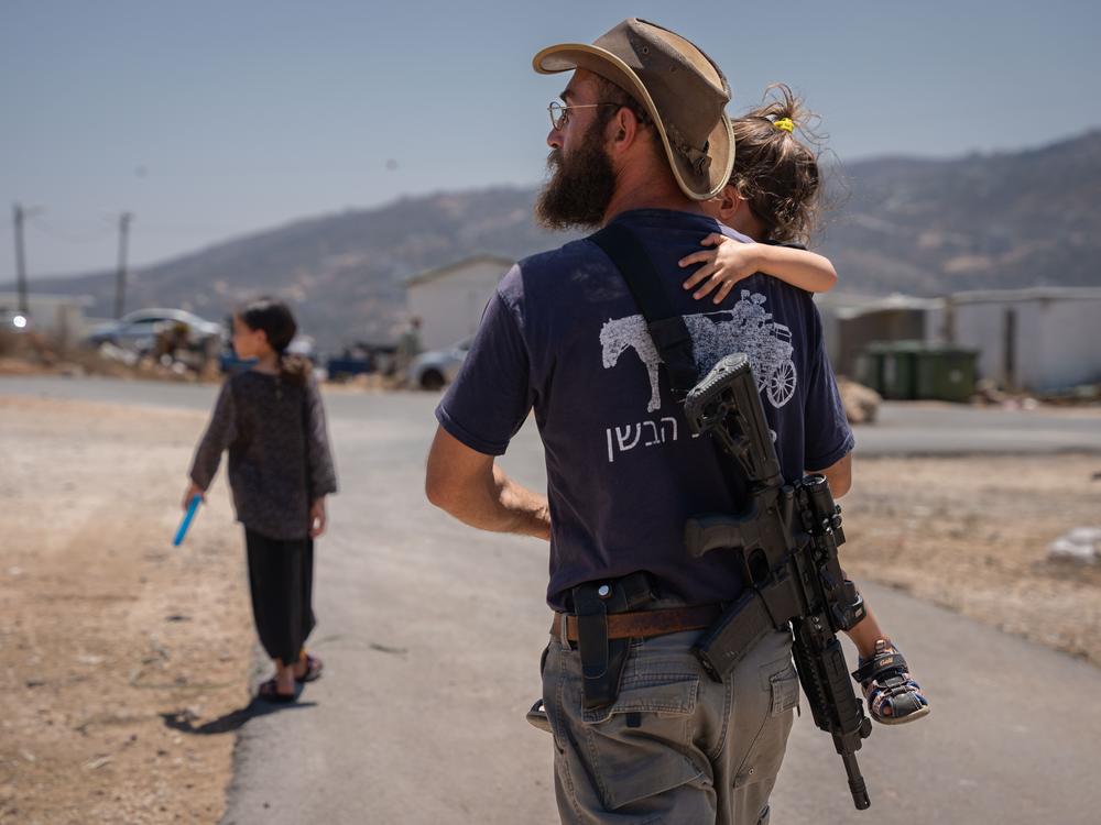 Malkiel Bar-Chai holds his daughter in the outpost settlement of Evyatar, which had recently received authorization from Israel, in the Israeli-occupied West Bank, on July 18.