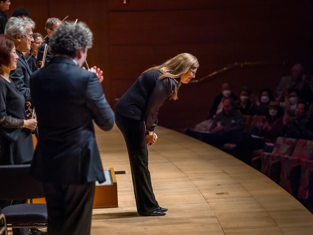 With conductor Gustavo Dudamel looking on, Ortiz takes a bow after a performance of her music by the Los Angeles Philharmonic.
