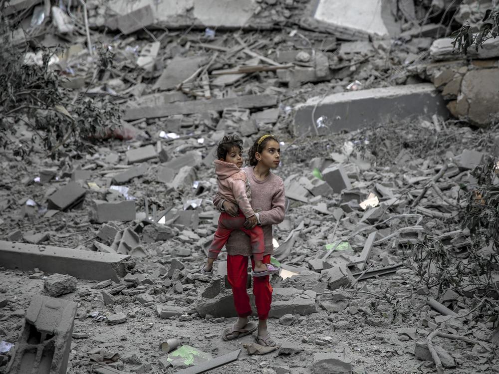 A Palestinian girl carries a child through the rubble of houses destroyed by Israeli bombardment in Gaza City on March 3, amid the ongoing conflict between Israel and the Hamas movement.
