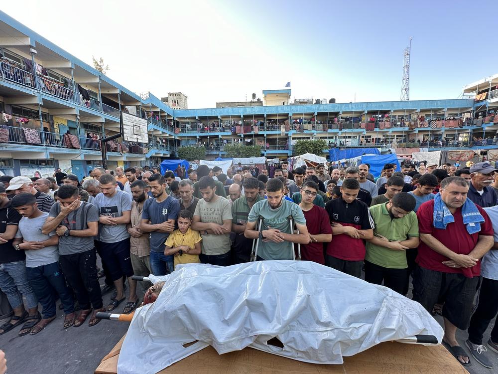 People pray over the body of a person killed in an Israeli airstrike on a U.N.-run school in Nuseirat, central Gaza, on Sept. 12. The U.N. says hundreds of Palestinians have been killed in U.N. schools that have been turned into shelters for tens of thousands of families displaced across the Gaza Strip.