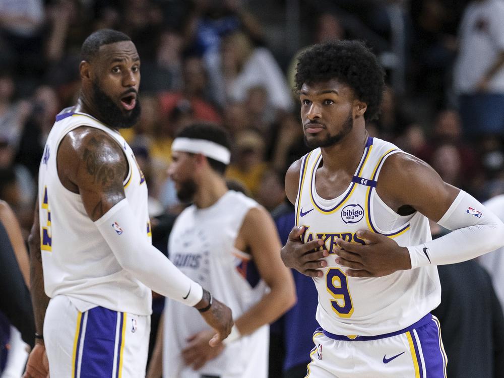 Los Angeles Lakers guard Bronny James (9), right, steps onto the court with Los Angeles Lakers forward LeBron James (23) during the first half of a preseason NBA basketball game Sunday in Palm Desert, Calif.