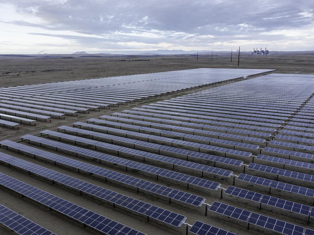 Panels that are part of San Juan Solar Project in northern New Mexico, with San Juan Generating Station smokestacks in the distance