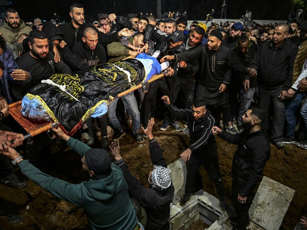 Mourners lower the flag-draped body to the grave of one of three men killed earlier in an Israeli air strike that targeted a car in Jenin in the occupied West Bank on March 20.