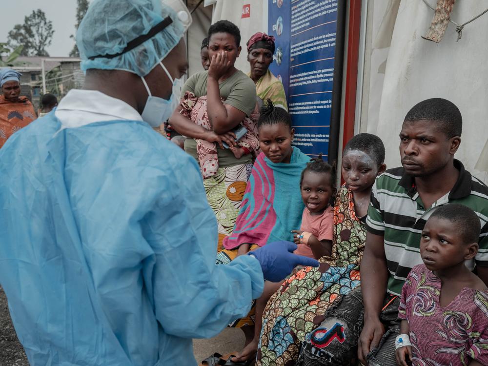 TOPSHOT - Patients listen to a doctor outside the consultation room of the Mpox treatment centre at Nyiragongo General Referral Hospital, north of Goma on August 17, 2024. With around 16,000 cases recorded since the beginning of the year, the DRC is the focus and epicentre of the epidemic that led the World Health Organisation (WHO) to trigger its highest level of alert at the international level on Wednesday. The province of South Kivu records around 350 new cases per week, according to Dr Justin Bengehya…