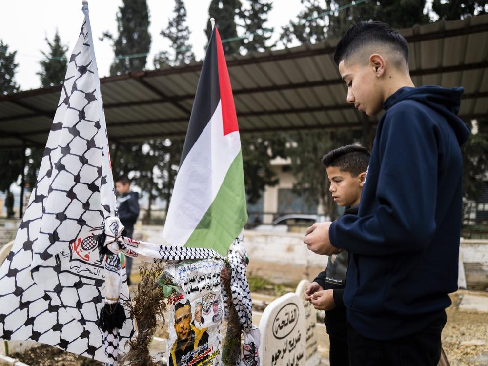 Noor Assi and his brother pray at their father’s grave every Friday.