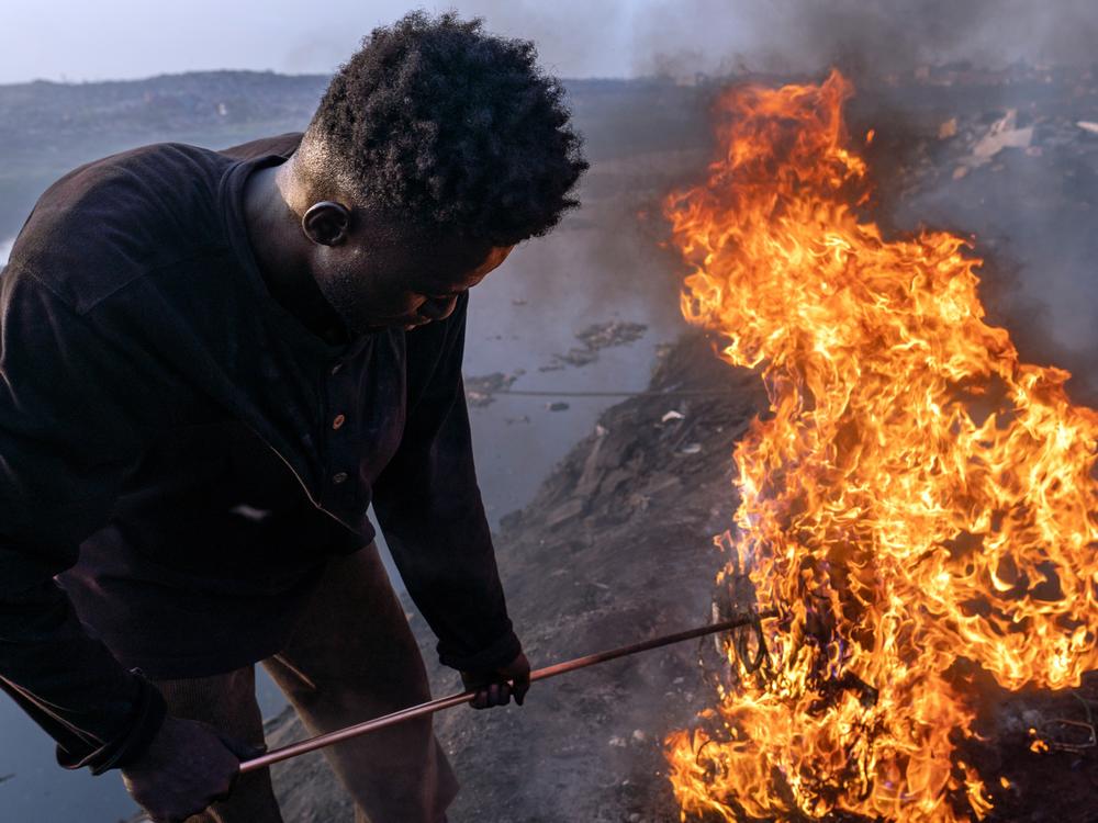 Simon Aniah, a 24-year-old from the Upper East region of Ghana, burns electrical cables to recover the copper wiring. In 2021, Upper East had the highest unemployment rate for young people in Ghana, forcing many to migrate to Accra to find work.