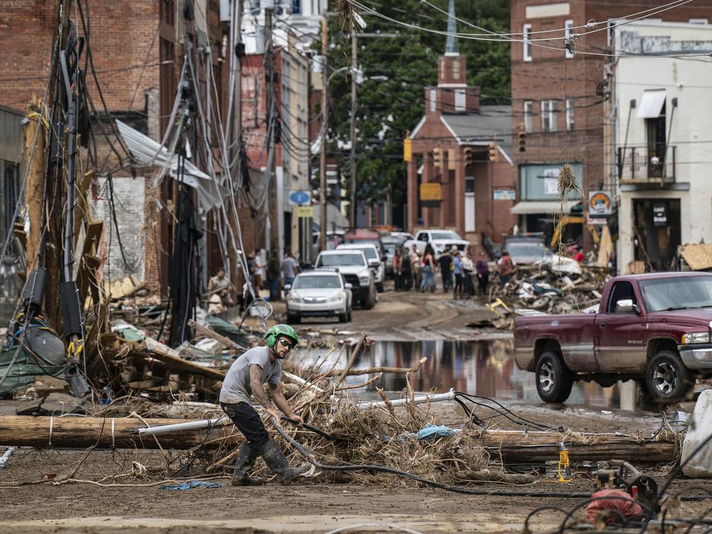 Workers, community members, and business owners clean up debris in the aftermath of Hurricane Helene in Marshall, North Carolina on Monday, Sept. 30, 2024.
